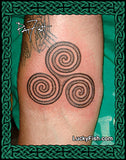 Tattoo of a triskele design on a person's arm with 'Lucky Fish' branding.