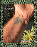 Tattoo of a Celtic triskele design on a wrist by Pat Fish with  'Lucky Fish' branding.