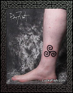 Triskele tattoo on a person's ankle with 'Lucky Fish' branding.