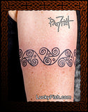 Tattoo of a wave design of La Tene spirals on a person's arm with 'Lucky Fish' branding.
