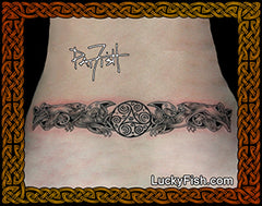 Tattoo design of two Celtic dogs and a circle of spirals on a person's lower back skin with Luckyfish.com branding