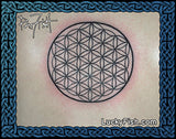 Tattoo of a flower of life symbol with Lucky Fish branding on a woman's back