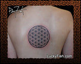 Tattoo of a flower of life symbol tattooed by Pat Fish on a person's back with Lucky Fish branding.