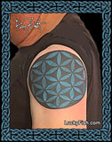 Person with a blue flower of life tattoo on shoulder, Lucky Fish branding coverup tattoo by Pat Fish