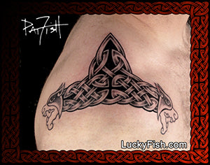 Triangular tattoo with Celtic design of lion dragons and knotwork on a person's arm, branded with LuckyFish.com.
