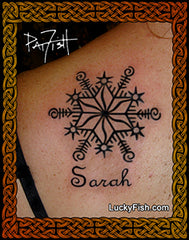 Tattoo of a snowflake star design with the name 'Sarah' on a person's arm,