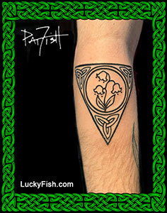 Tattoo of a triangular Celtic design with lily of the valley flowers on a person's arm, with 'LuckyFish.com' branding.