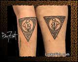 Two matching tattoos of a stylized lily of the valley flower design on an arm and leg with 'Lucky Fish' branding.