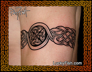 A black and gray tattoo design of a Celtic fcross and armband on human skin showing a Celtic knot pattern, framed by an ornate brown border with the LuckyFish.com watermark.