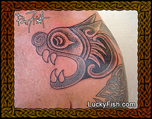 Celtic lion tattoo on shoulder skin with 'Lucky Fish' branding. Design from the Book of Kells.