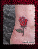 tiny rose bud tattoo on a foot