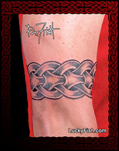 A close-up of a person's skin showing a black and gray tattoo of interwoven Nordic-style knot shapes, with a red border and the text LuckyFish.com at the bottom.