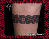 A close-up of a person's forearm showing a horizontal Norse knot tattoo armband with red and black details and LuckyFish branding