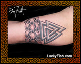 A close-up of a tattoo on the inside of a person's forearm featuring a Viking knot design, framed by an ornate brown border with the LuckyFish.com website URL at the bottom.