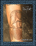 Tattoo of a Pictish bear and spiral design wrapping around a person's arm, with 'Lucky Fish' branding.