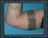 Person wearing a Celtic knot arm band with 'Lucky Fish.com' branding.