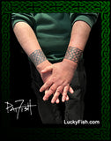 Person with Celtic band tattoos on arms holding hands with 'LuckyFish.com' branding.