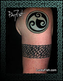 Tattoo of a Celtic knot design and arm band on a person's arm with 'LuckyFish.com' branding.