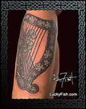 Celtic harp tattoo with intricate designs on a person's leg, branded 'Lucky Fish'.