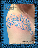 A tattoo design photo showing a blue swirling Pictish-style pattern applied to a person's upper shoulder. The image has a decorative blue border and the branding text LuckyFish.com