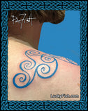 A close-up of a person's shoulder and neck showing a blue Pictish spiral tattoo design on the upper back/shoulder, with a decorative blue knot border around the image and the text LuckyFish.com and PatFish.
