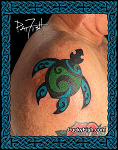 Tattoo of a green and black honu sea turtle design on a person's shoulder with 'Lucky Fish' branding.