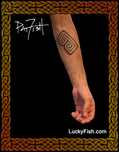 Tattoo of a Taino spiral petroglyph design on a forearm with 'LuckyFish.com' branding.