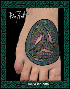 Three salmon fish in a colorful Celtic knot tattoo on a foot with 'Lucky Fish' branding.