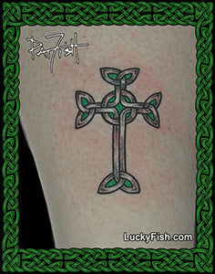 A Celtic-style cross tattoo design shown on skin, with green and black linework and a green decorative border around the image. The text 'LuckyFish.
