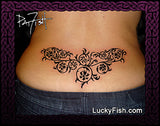 Floral tapestry tattoo design on a person's lower back with 'Lucky Fish' branding.