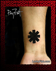 A black geometric chaos symbol tattoo applied to a person's wrist framed by a red Celtic-style border with the brand name LuckyFish.com at the bottom.