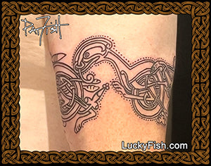 Celtic knot tattoo on a person's arm with Celtic cats from the Book of Kells and 'LuckyFish.com' branding.