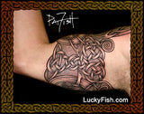 Tattoo of a Celtic knot design on the inside of a person's arm with 'Lucky Fish' branding.