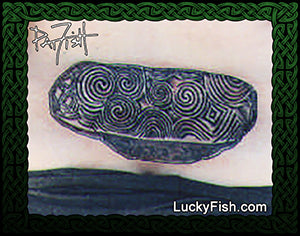 kerbstone of Newgrange in Ireland with spiral patterns on surface, featuring LuckyFish.com branding.