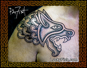 Tattoo of a stylized medieval manuscript lion head design on skin, with 'Lucky Fish' branding.