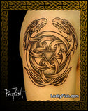 A large black and gray Celtic knotwork tattoo featuring a central knot and coiled double headed dragon design, shown on human skin with a decorative border and LuckyFish.com watermark.