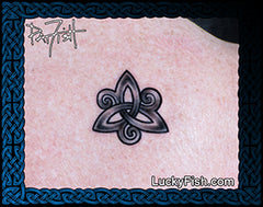 A close-up of a tattoo applied to skin, showing a black Celtic triangular knot design. The image has a url of LuckyFish.com and signature of Pat Fsh